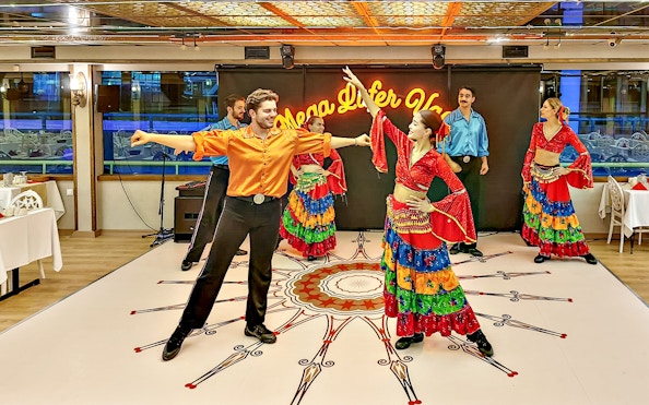 Dancers performing in colorful costumes during a dinner cruise show.