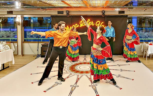 Dancers performing in colorful costumes during a dinner cruise show.