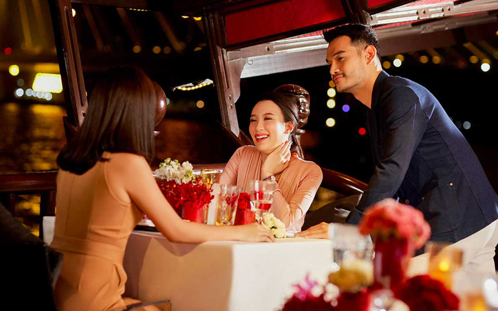 Guests enjoying dinner on the Manohra Cruise with city lights in the background.