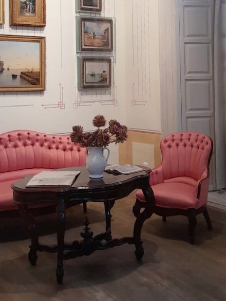 Seating area with pink chairs and paintings inside Picasso's birthplace museum in Malaga.