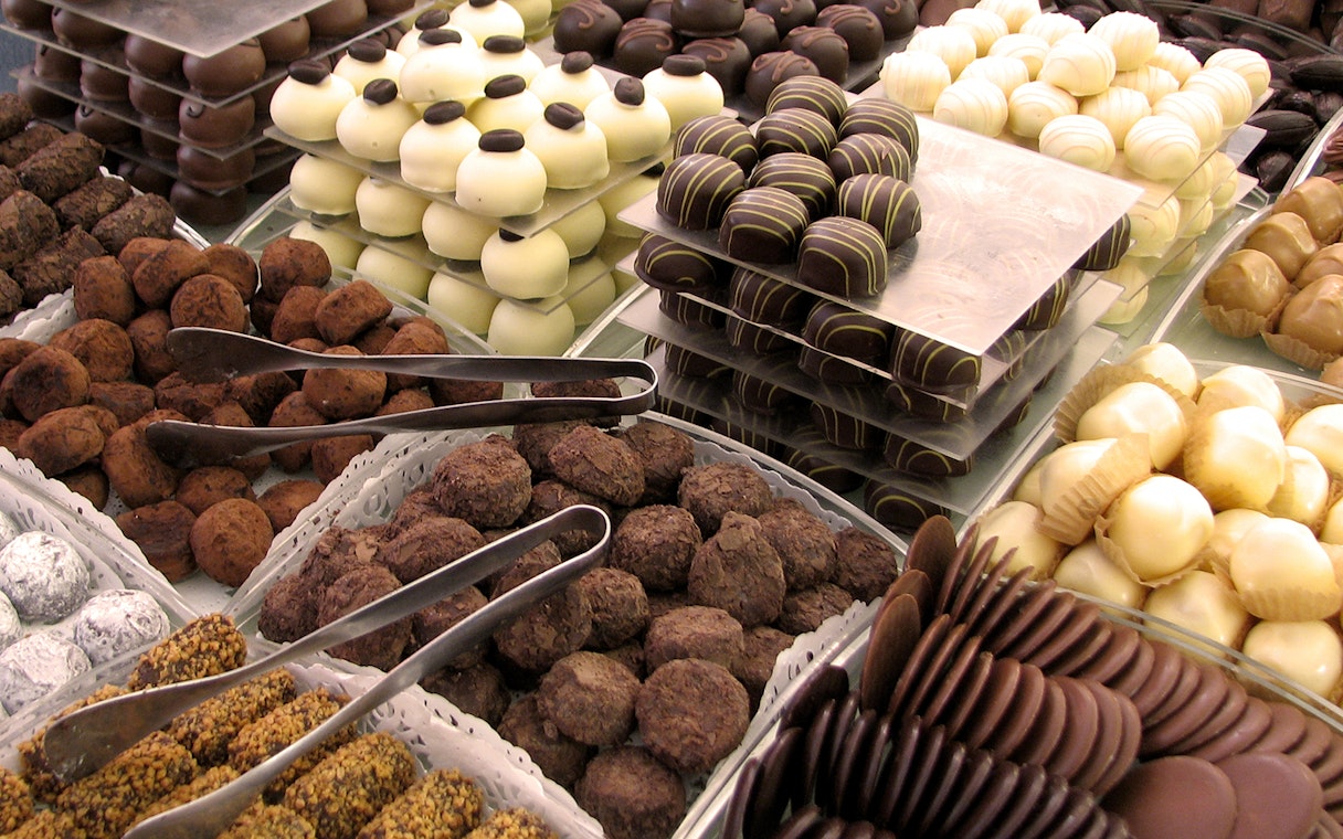 Assorted chocolates displayed at a renowned chocolatier in Bruges, featuring a variety of truffles and pralines.