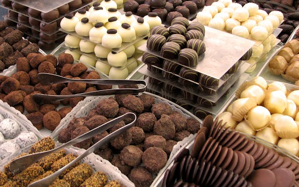 Assorted chocolates displayed at a renowned chocolatier in Bruges, featuring a variety of truffles and pralines.