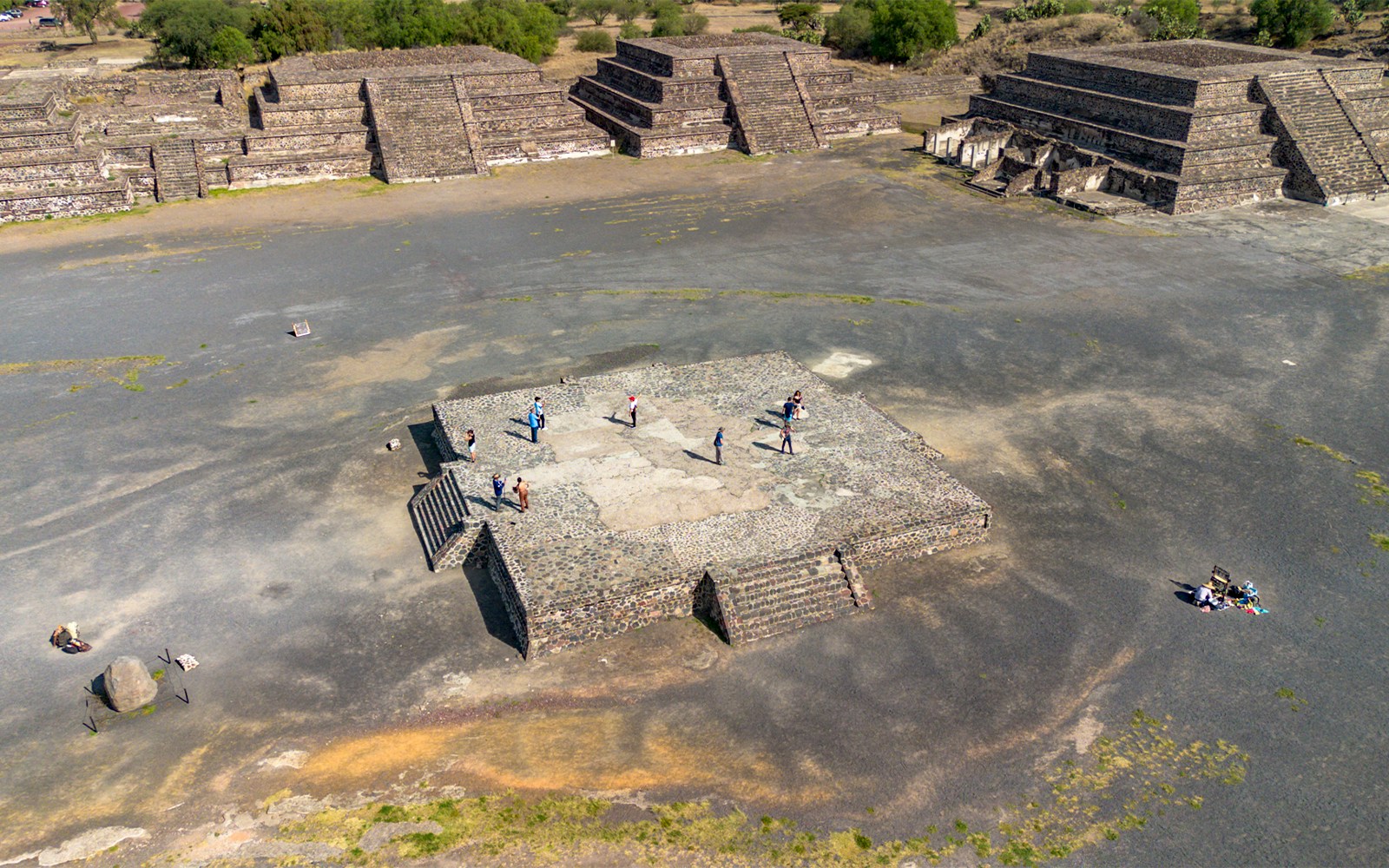 Aerial view of tourists exploring the Avenue of the Dead, Teotihuacan, with pyramids in the background.