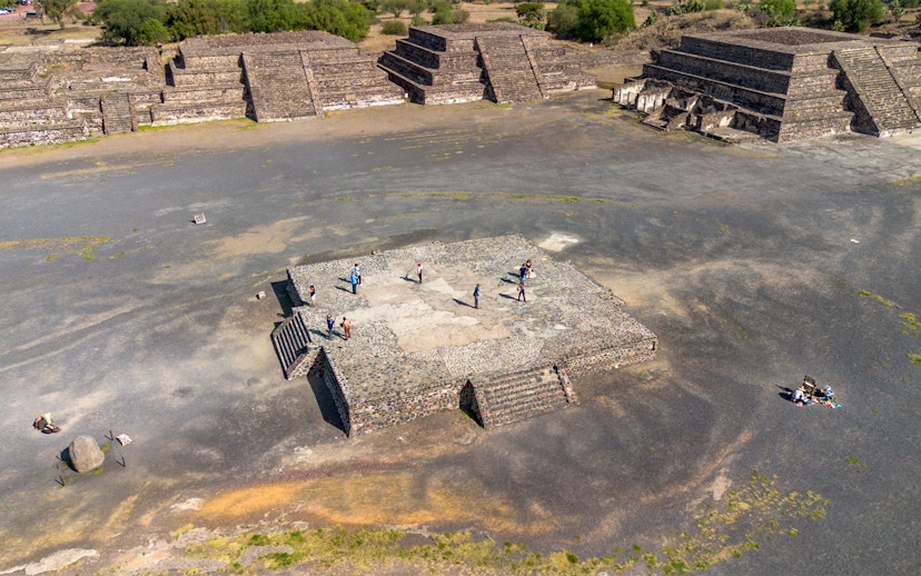 Aerial view of tourists exploring the Avenue of the Dead, Teotihuacan, with pyramids in the background.