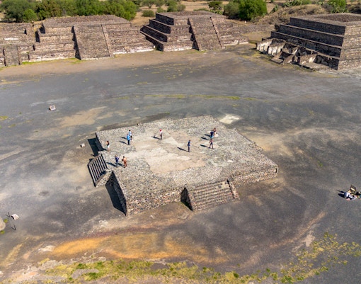 Aerial view of tourists exploring the Avenue of the Dead, Teotihuacan, with pyramids in the background.