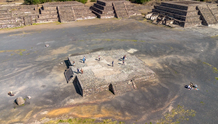 Aerial view of tourists exploring the Avenue of the Dead, Teotihuacan, with pyramids in the background.