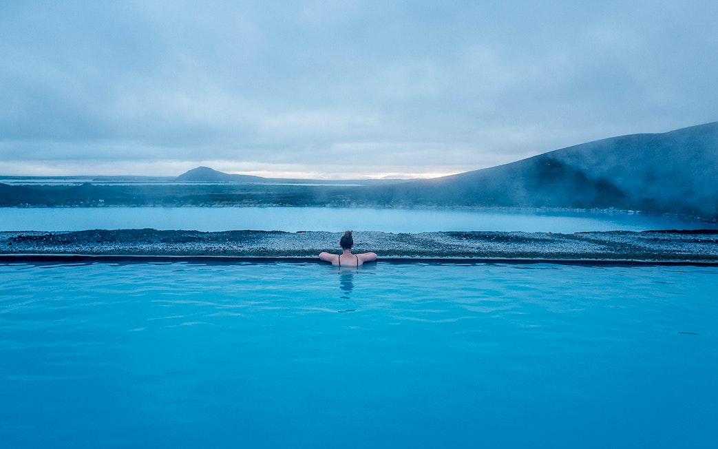 Guest relaxing in Myvatn Nature Baths with scenic Icelandic landscape.