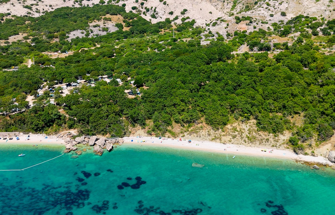 Barjoska Beach aerial view with turquoise water and lush green forest.