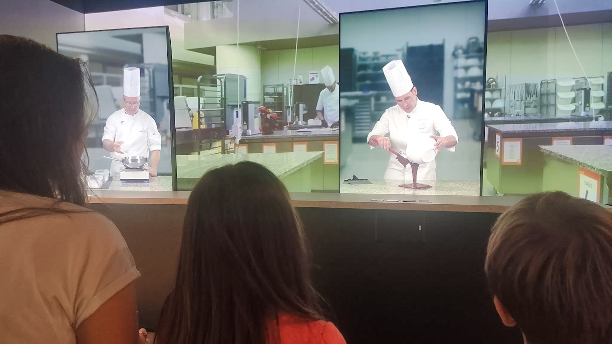 Visitors watching a digital chocolate-making demonstration at Choco-Story Paris.