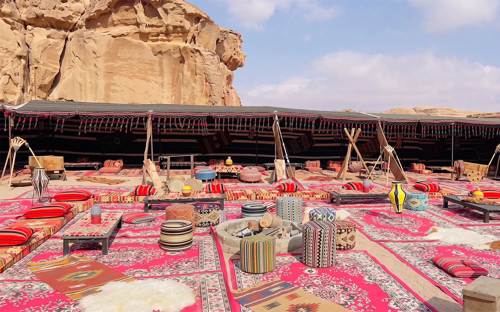 Desert camp setup with colorful rugs and cushions in Wadi Rum, Jordan.