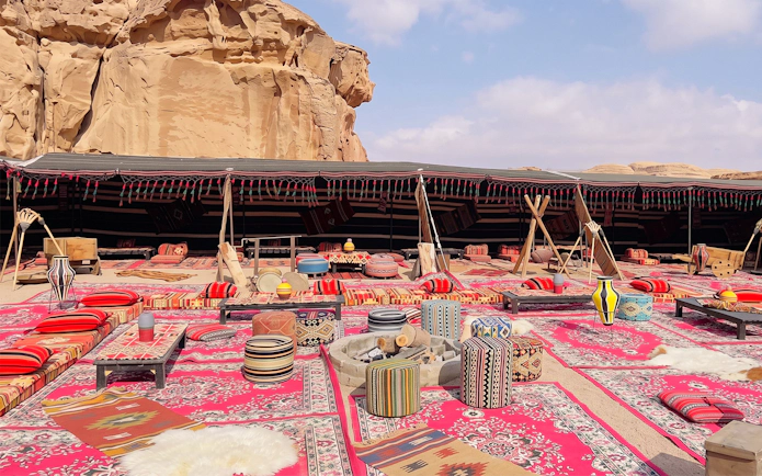 Desert camp setup with colorful rugs and cushions in Wadi Rum, Jordan.