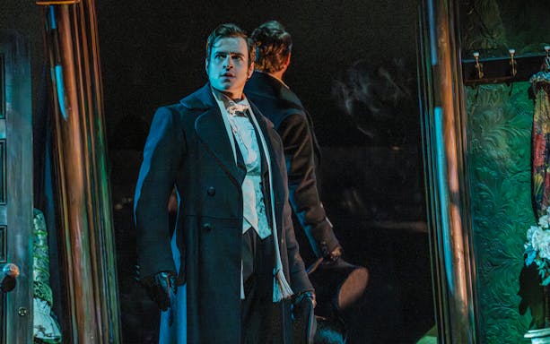 Actor in Victorian attire on stage during Phantom of the Opera production.