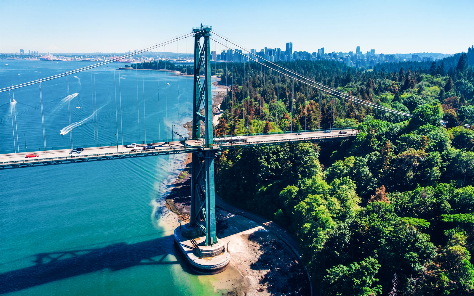 Lions Gate Bridge spanning over water with Vancouver skyline and Stanley Park in view.