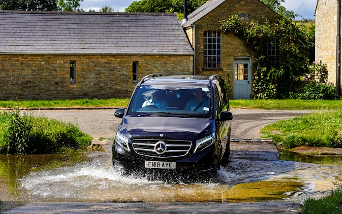 Van crossing a shallow stream in the Cotswolds countryside near Oxford.