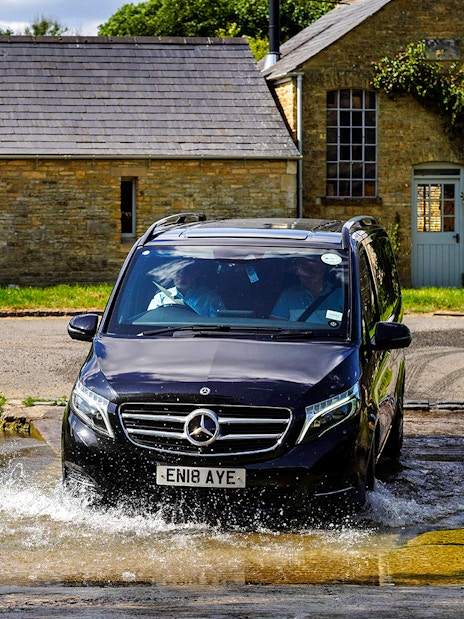 Van crossing a shallow stream in the Cotswolds countryside near Oxford.