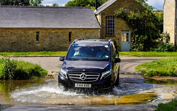 Van crossing a shallow stream in the Cotswolds countryside near Oxford.