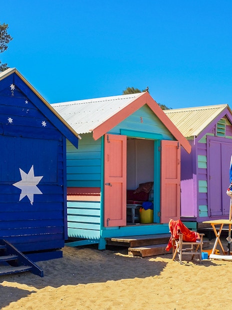 Colorful Brighton Beach Boxes lined up on sandy beach, Melbourne, Australia.