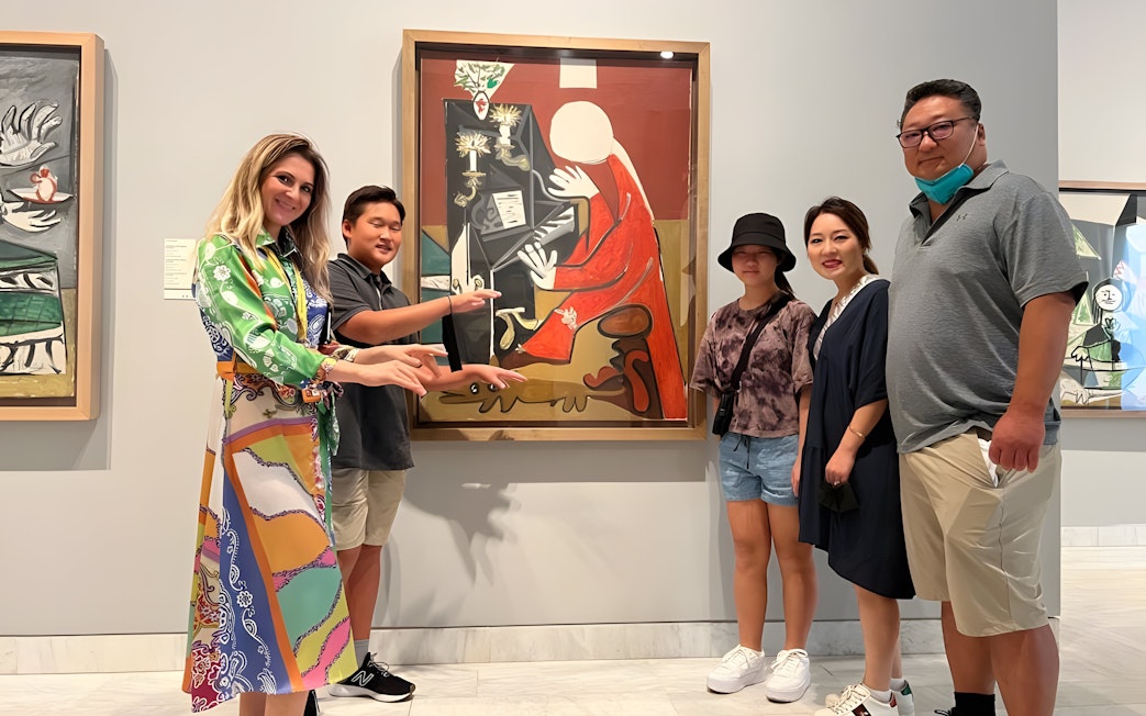 Tourist group with guide at Picasso Museum viewing artwork in Barcelona.