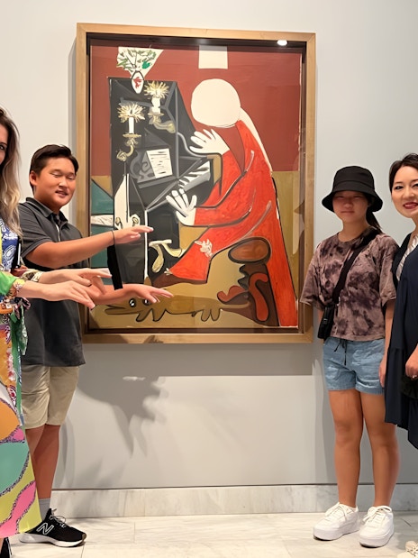 Tourist group with guide at Picasso Museum viewing artwork in Barcelona.