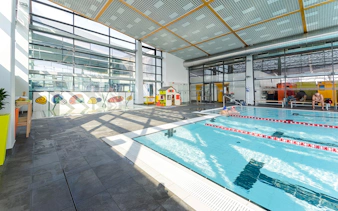 Indoor pool area at Paskal Thermal Bath, Budapest with swimmers and colorful wall art.