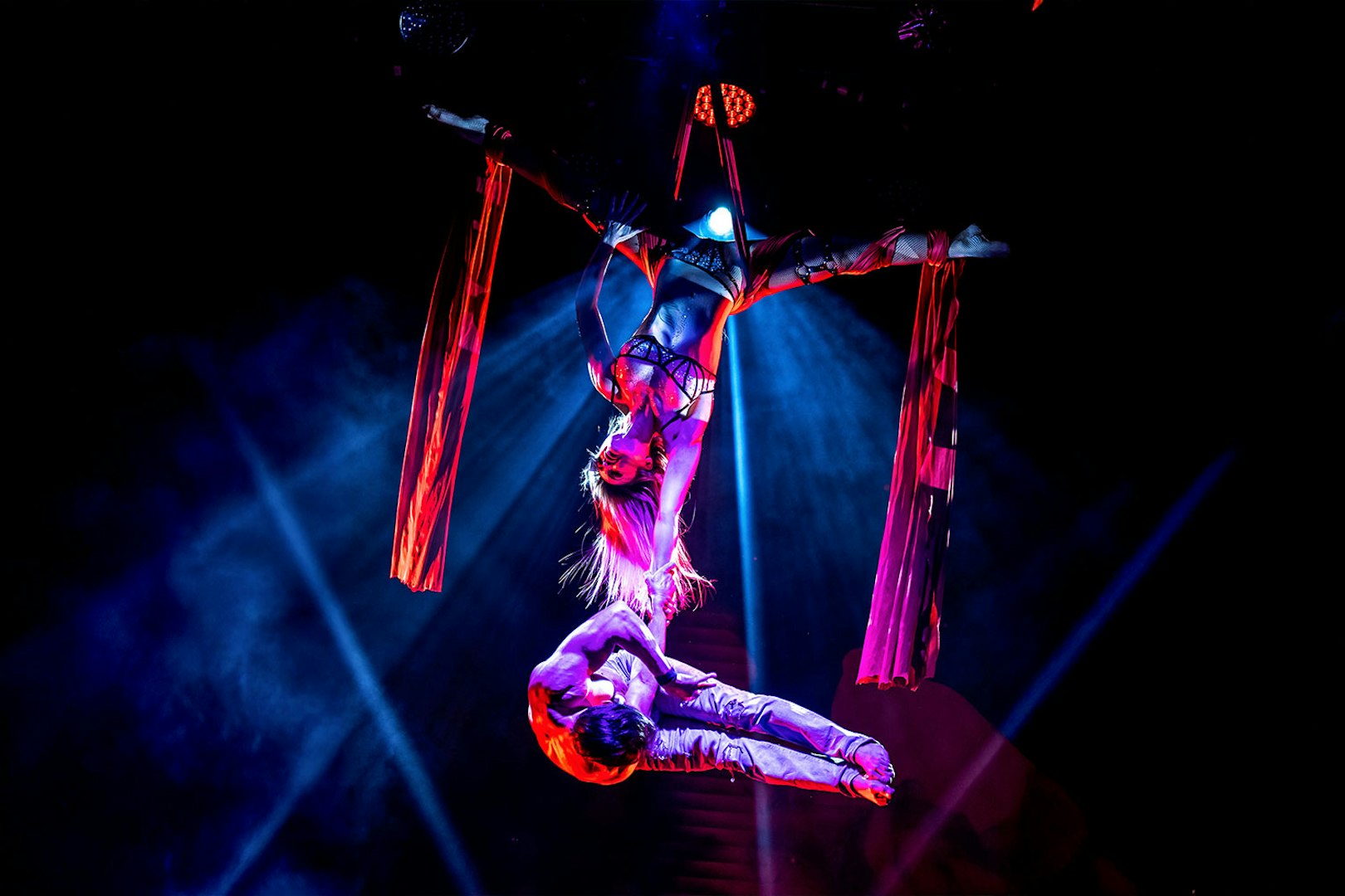 Aerial performers in a Rouge-themed show with red silk ribbons.
