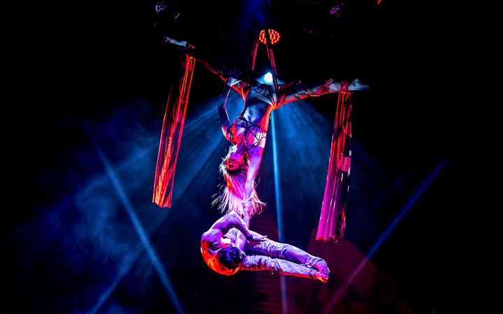 Aerial performers in a Rouge-themed show with red silk ribbons.