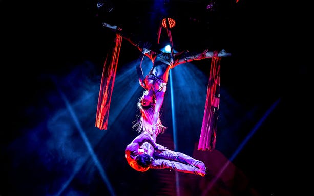 Aerial performers in a Rouge-themed show with red silk ribbons.