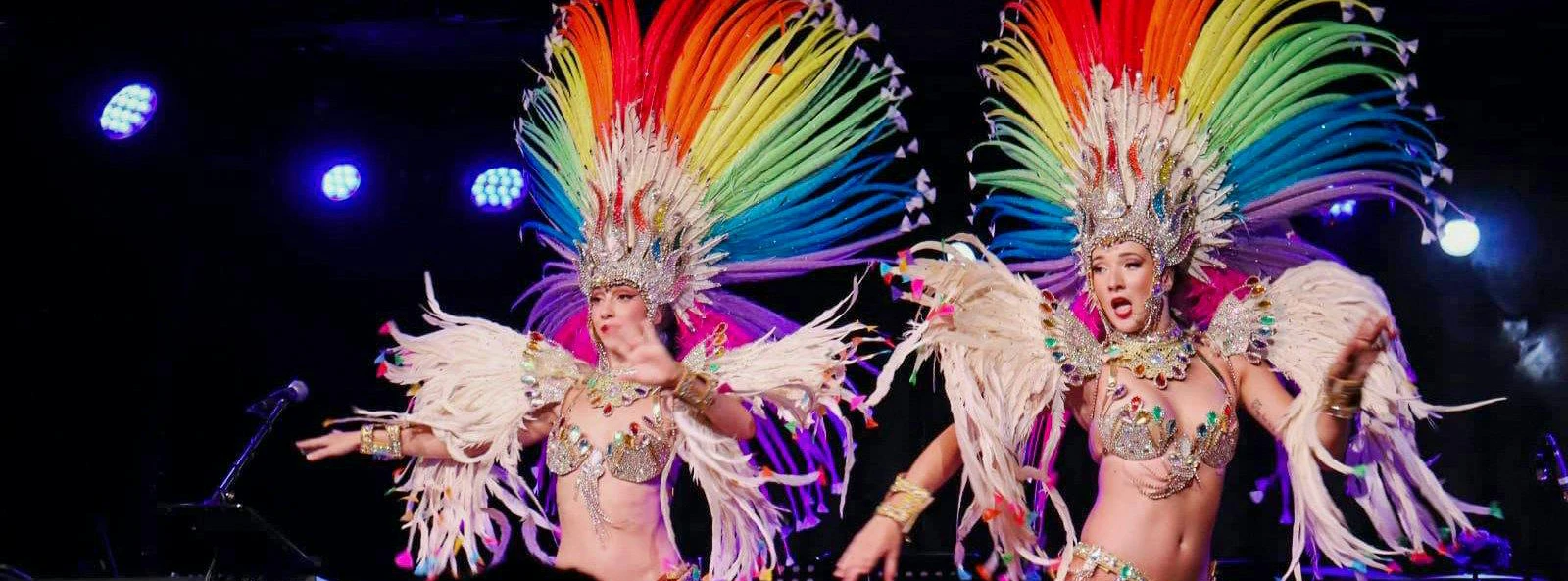 Performers in vibrant feathered costumes at Oh!César Cabaret Caribbean Nights Show.