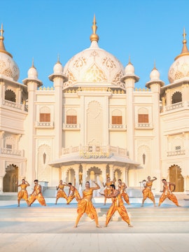 Dancers performing in front of ornate building at Bollywood Park Dubai, Dubai Parks and Resorts.