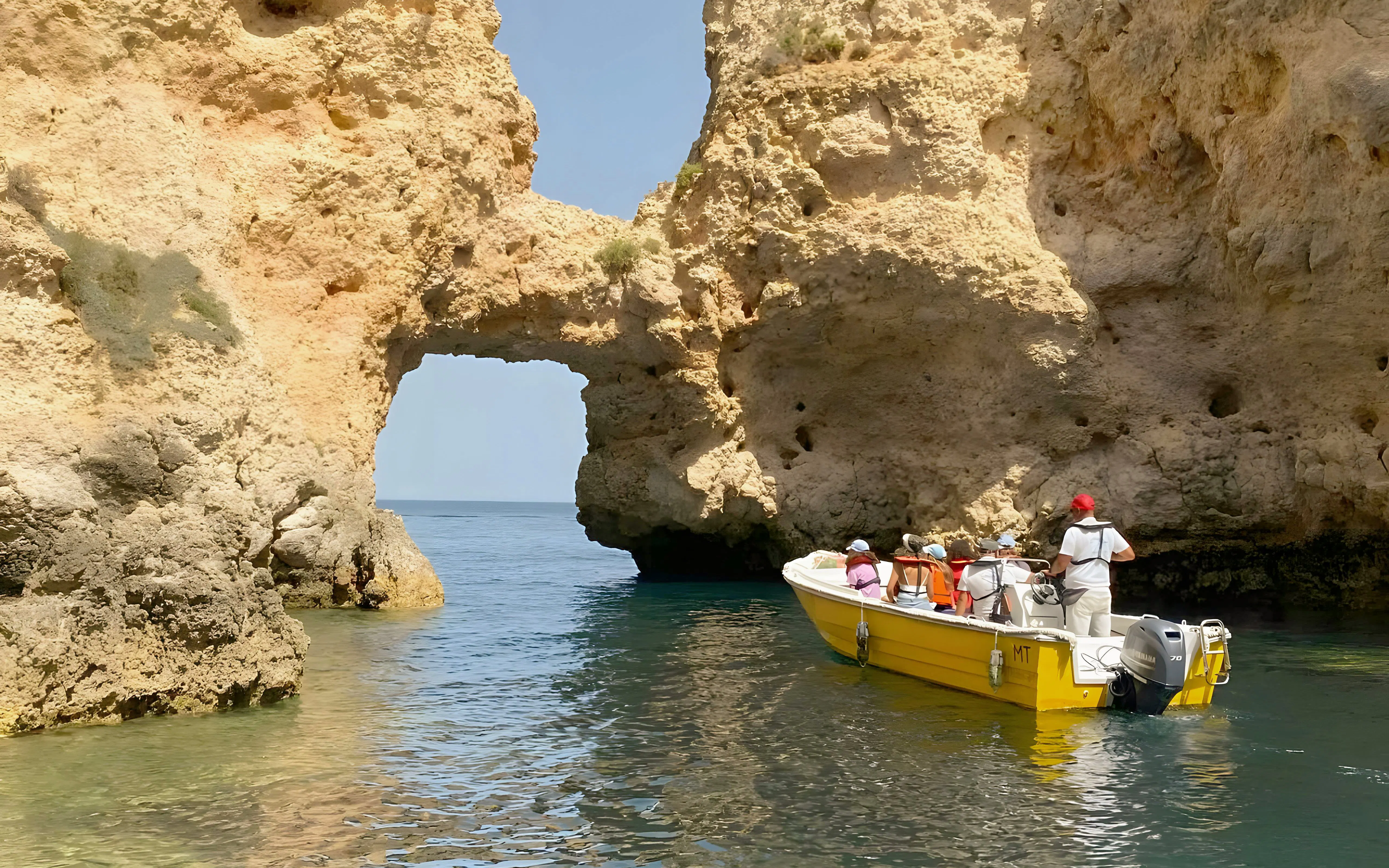 Tourists on a yellow boat exploring Ponta da Piedade rock formations in Lagos, Portugal.