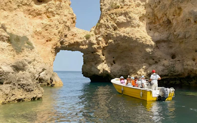 Tourists on a yellow boat exploring Ponta da Piedade rock formations in Lagos, Portugal.