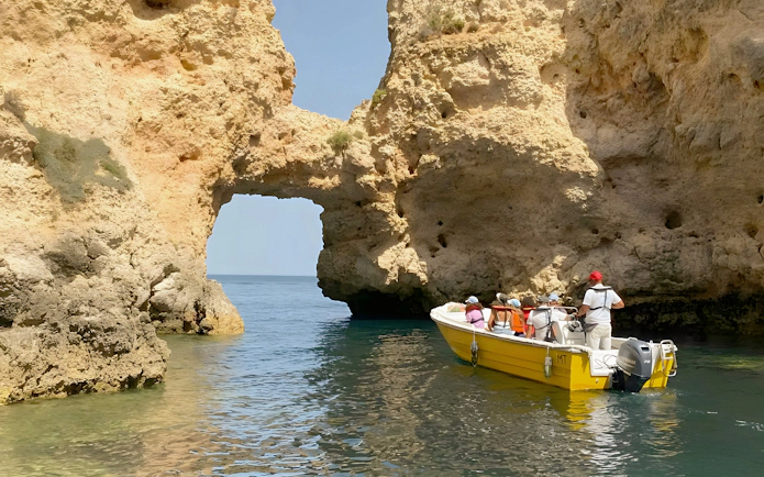 Tourists on a yellow boat exploring Ponta da Piedade rock formations in Lagos, Portugal.