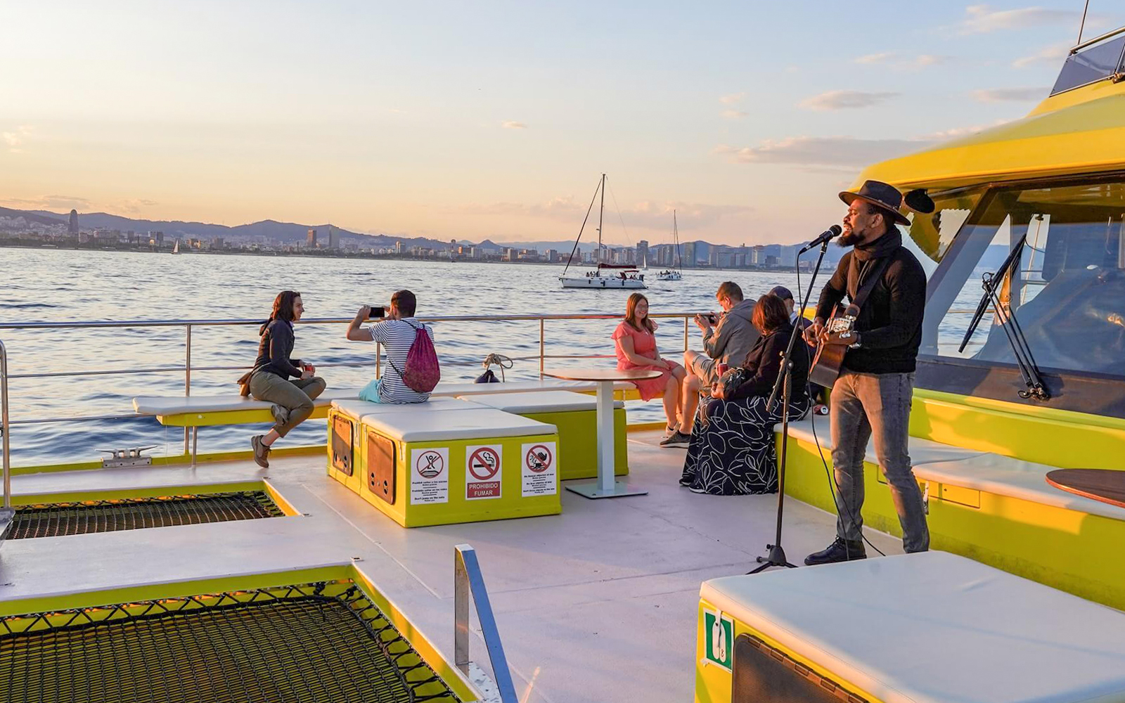 Musician performing on a Barcelona catamaran cruise at sunset.