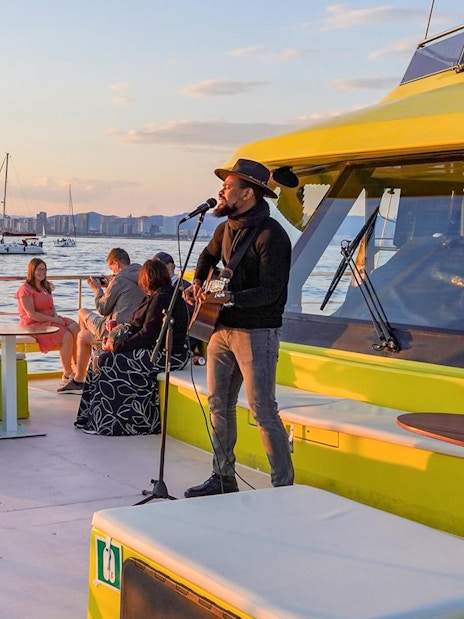Musician performing on a Barcelona catamaran cruise at sunset.