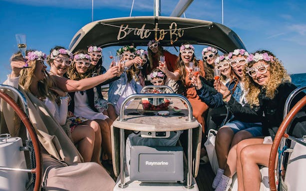 Group celebrating on a private boat in Gdansk, wearing floral headbands and holding drinks.