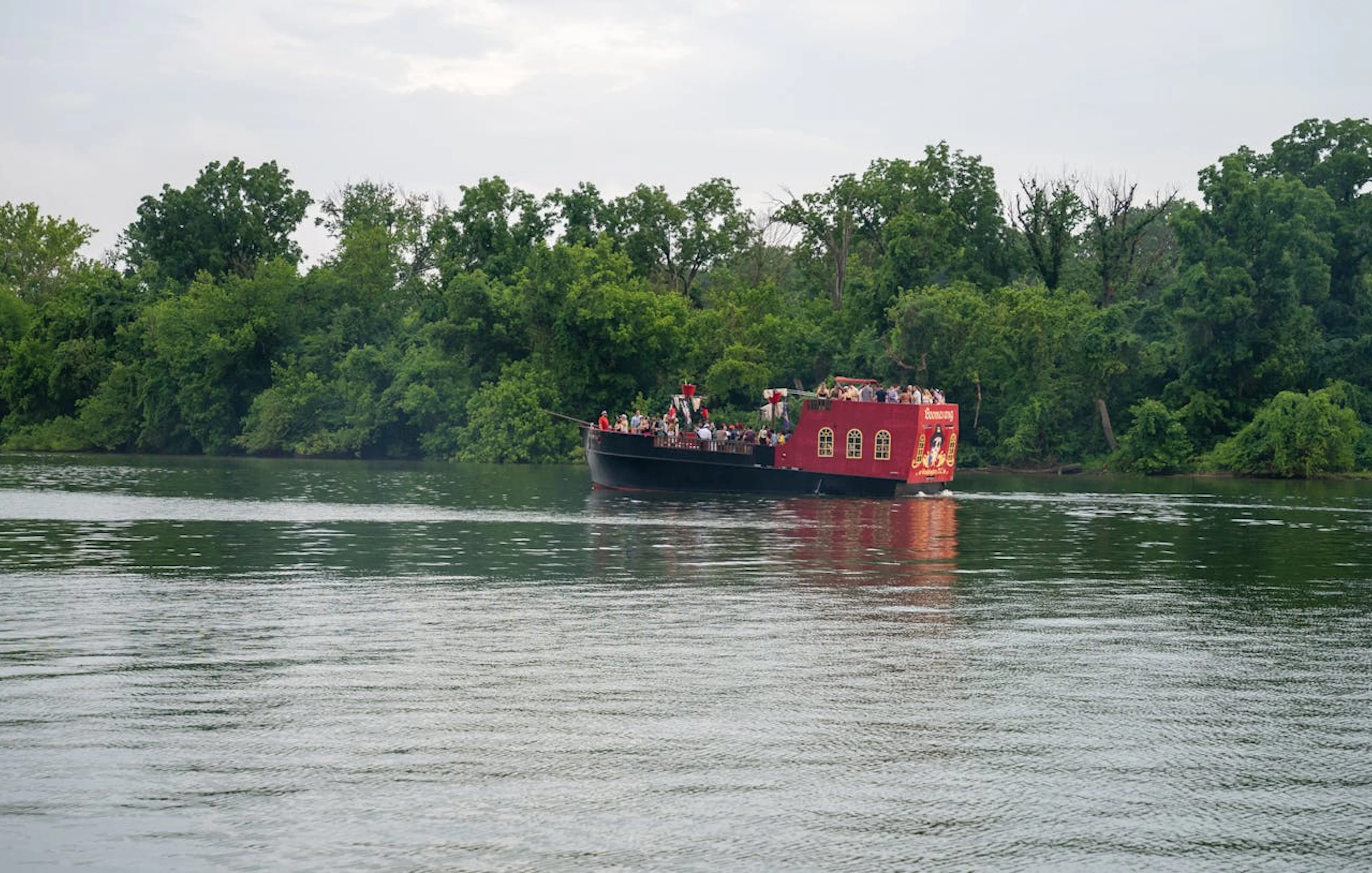 Boomerang Pirate Ship on river with partygoers, surrounded by trees, Washington DC.
