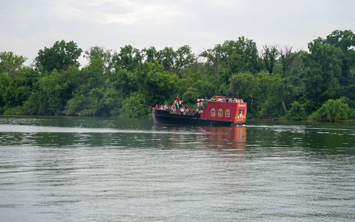 Boomerang Pirate Ship on river with partygoers, surrounded by trees, Washington DC.