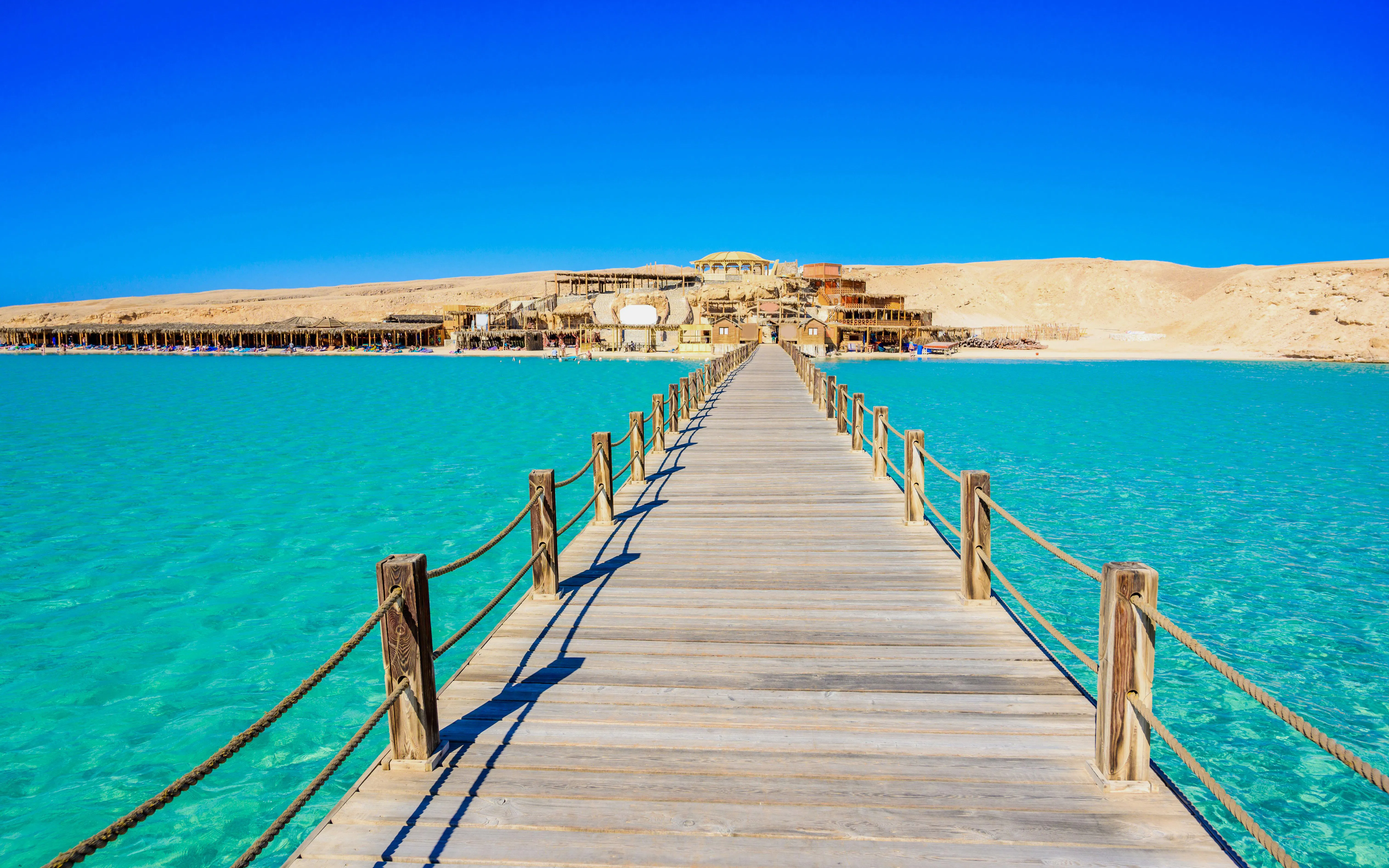 Wooden pier leading to Orange Bay Beach on Giftun Island, Hurghada, with clear azure water.