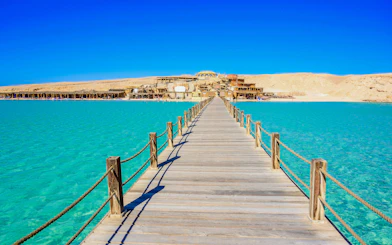 Wooden pier leading to Orange Bay Beach on Giftun Island, Hurghada, with clear azure water.