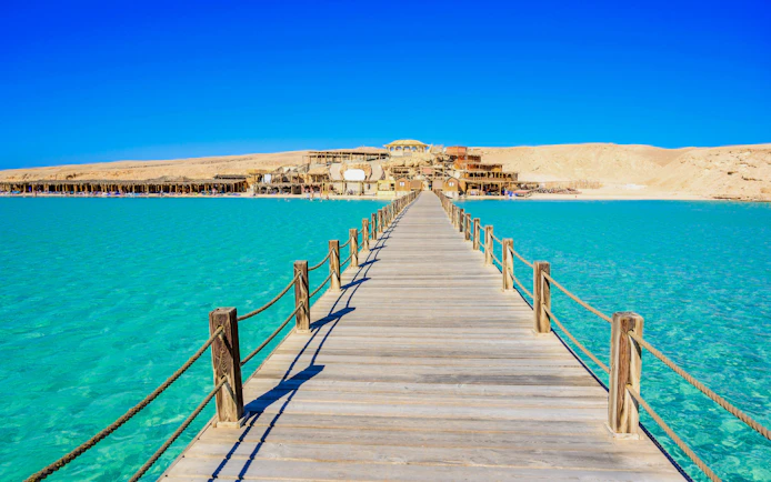 Wooden pier leading to Orange Bay Beach on Giftun Island, Hurghada, with clear azure water.