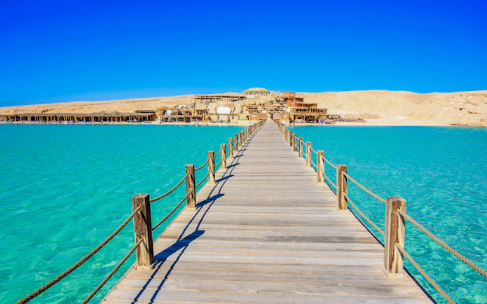 Wooden pier leading to Orange Bay Beach on Giftun Island, Hurghada, with clear azure water.