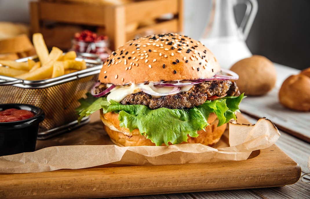 Cheeseburger with lettuce, tomato, and cheese on a sesame seed bun.