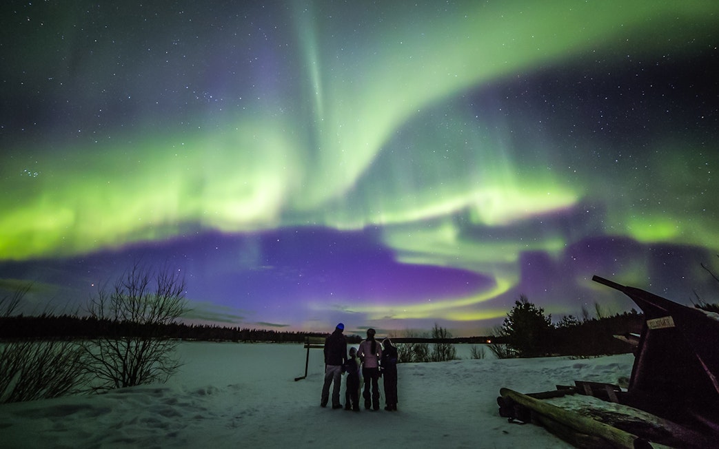 Family watching Northern Lights in Levi, Finland.