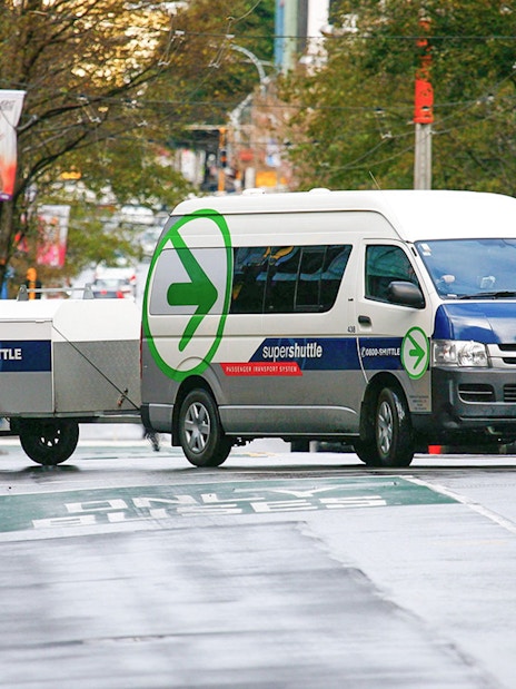 Super Shuttle van on city street for airport transfers.