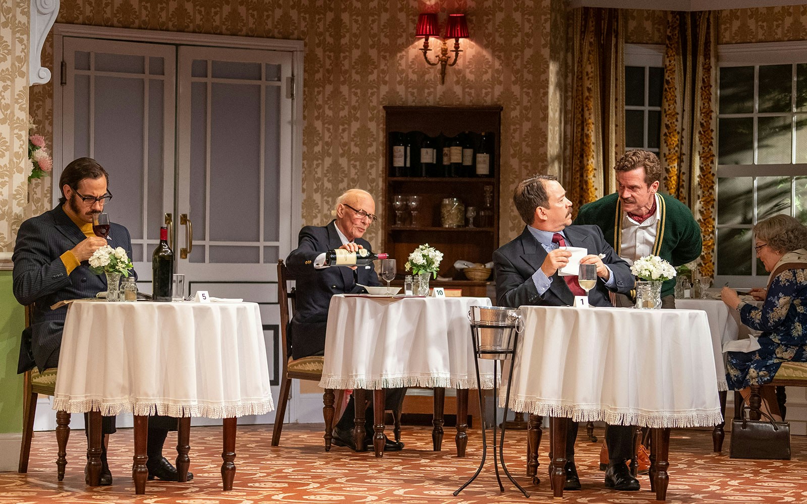 Dining scene from Fawlty Towers with guests at tables in a vintage restaurant setting.