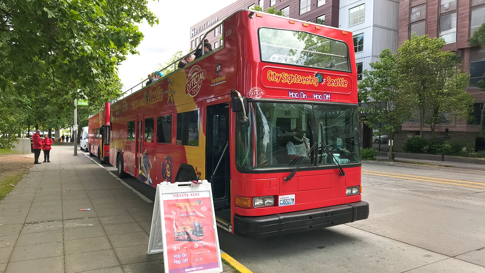 City Sightseeing bus at Seattle bus stop with ticket sign nearby.
