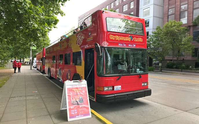 City Sightseeing bus at Seattle bus stop with ticket sign nearby.