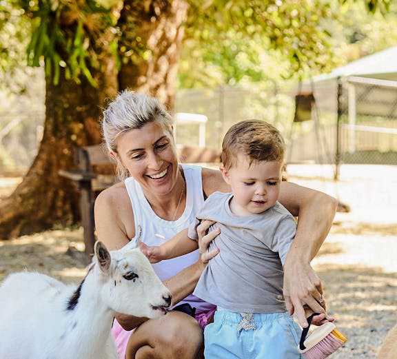 Child and adult interacting with goats at Sunshine Coast farm.