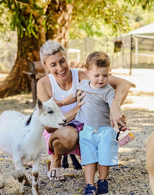 Child and adult interacting with goats at Sunshine Coast farm.