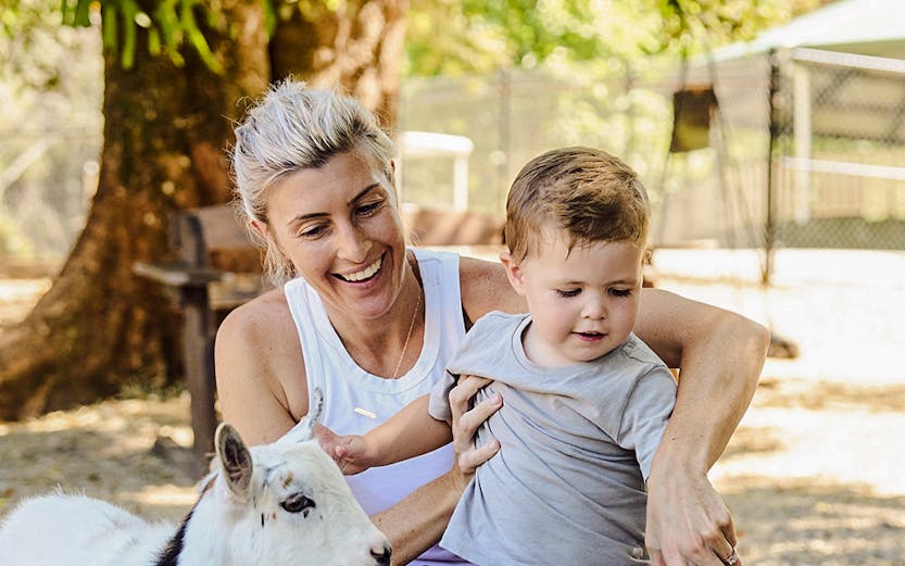 Child and adult interacting with goats at Sunshine Coast farm.